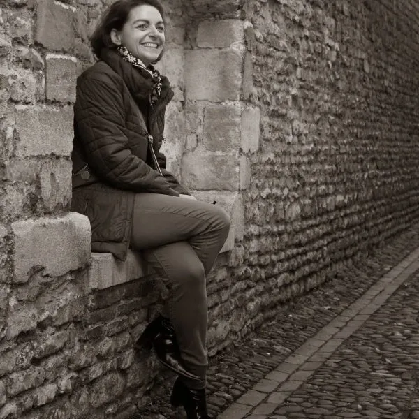 Charlotte Lestienne, assise sur un muret de pierre dans une ruelle de Cambridge